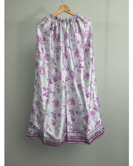 Floral dress with purple flowers on a hanger against a gray background