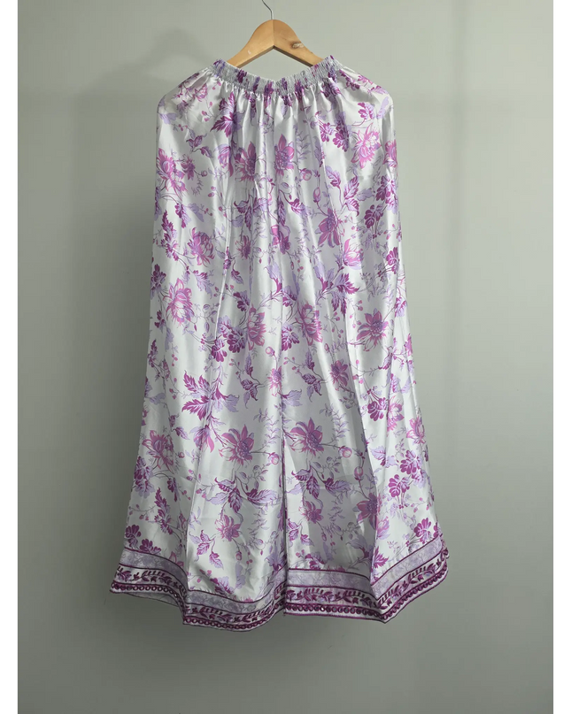 Floral dress with purple flowers on a hanger against a gray background